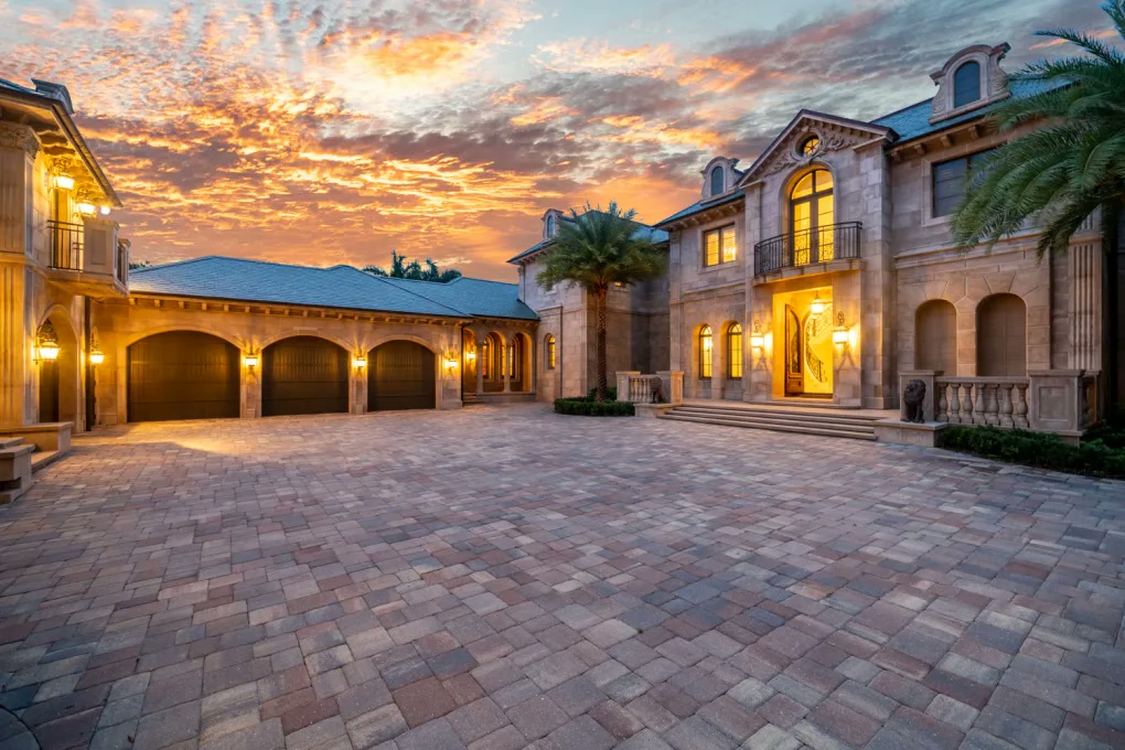 Wide motor court and illuminated stone facade at dusk