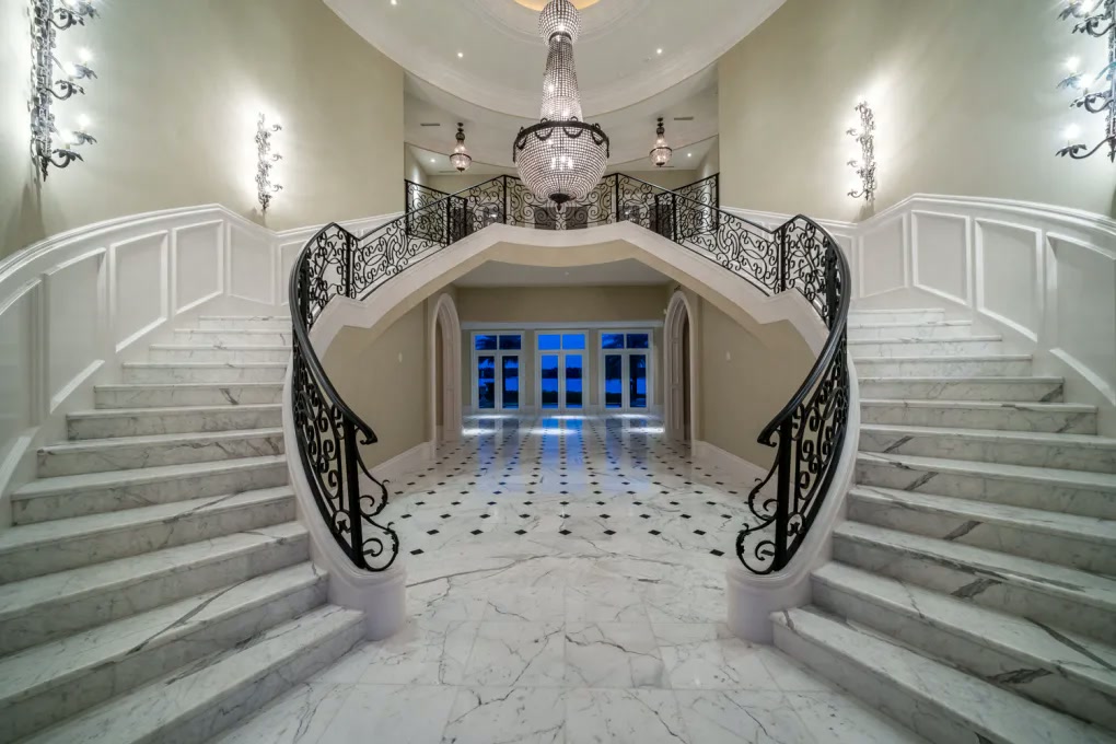 Double staircase and marble entry hall with decorative ironwork