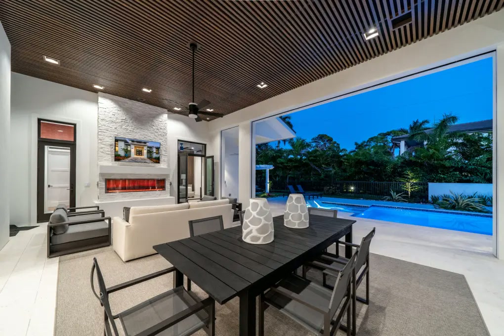 Covered outdoor dining beside the pool and linear fireplace
