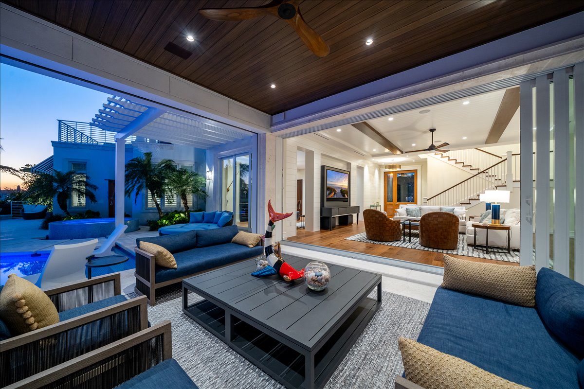 Covered outdoor living room opening to the waterfront pool