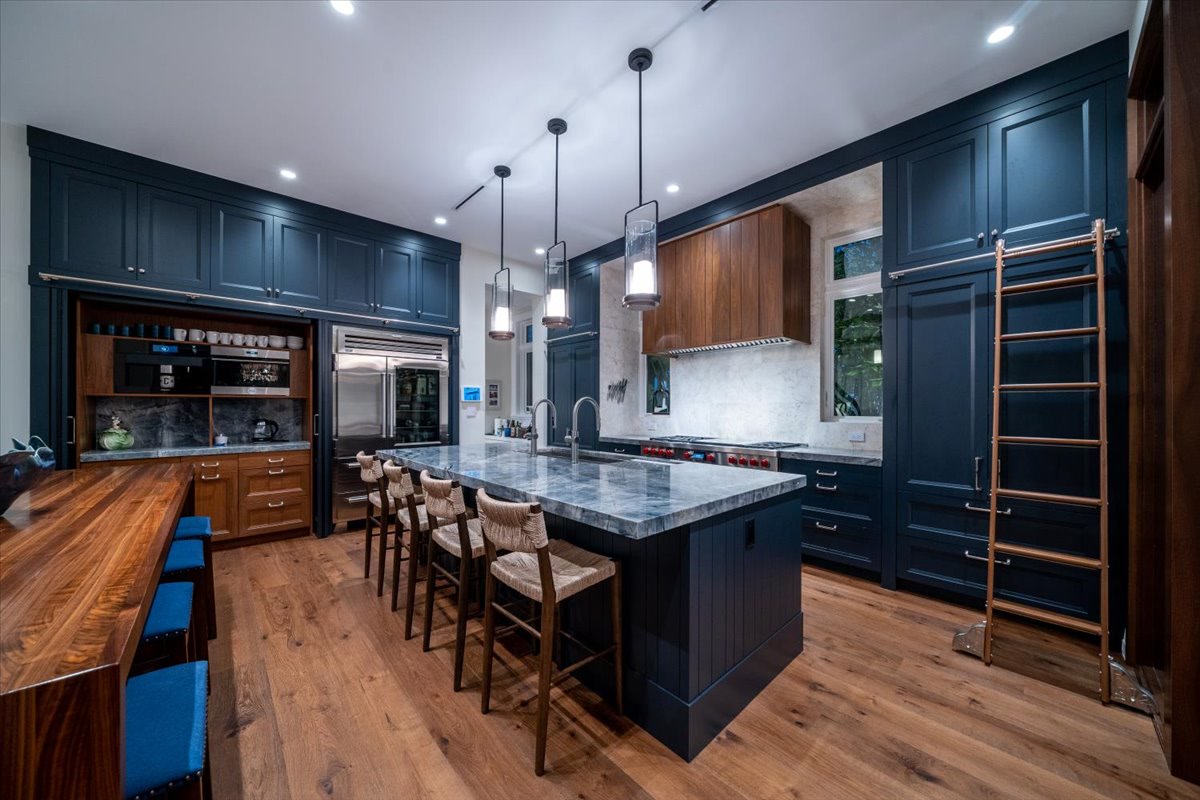 Dark custom kitchen with wood island and brass library ladder