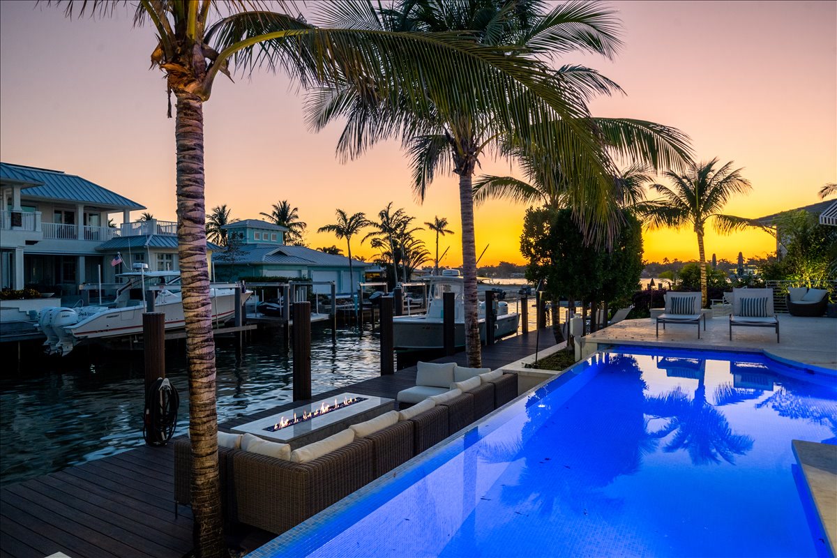 Waterfront pool and dock beneath a vivid Naples sunset