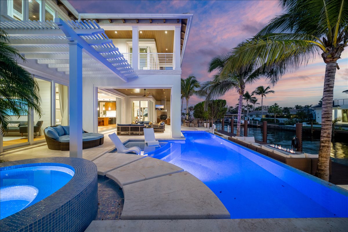 Rear exterior and illuminated pool photographed at twilight