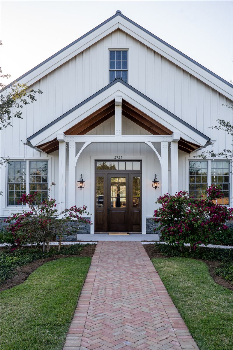 White gabled entry framed by flowering landscaping
