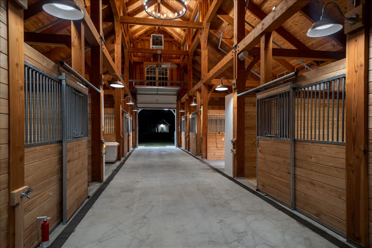 Symmetrical timber stable aisle with individual stalls
